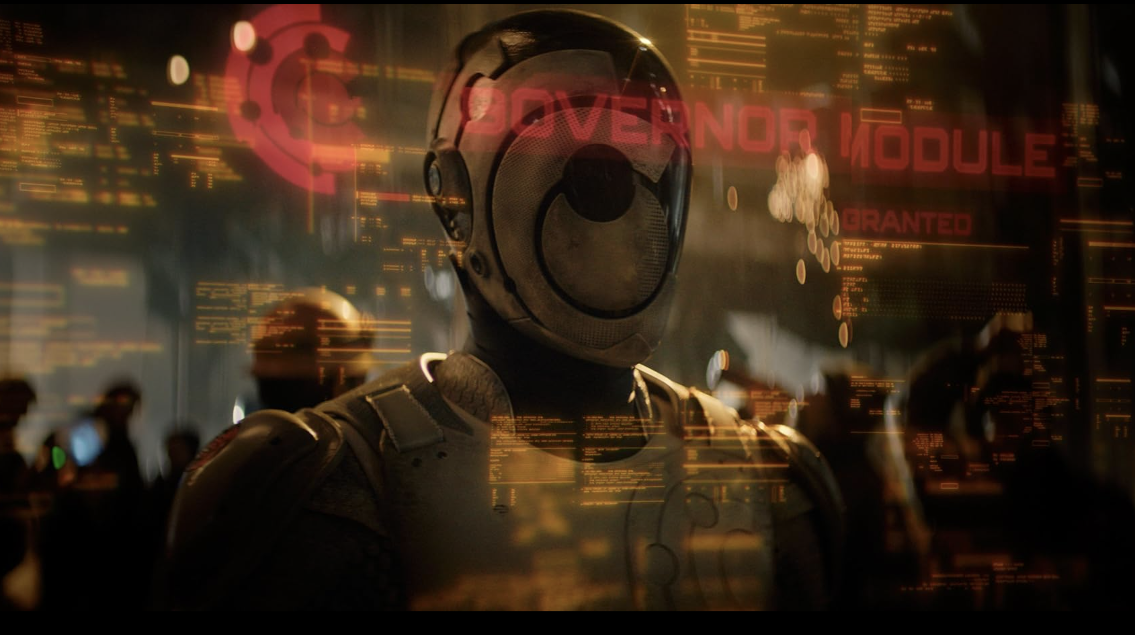 A robot (man in full body armor with face covered) stands in front of a computer screen with transparent text.